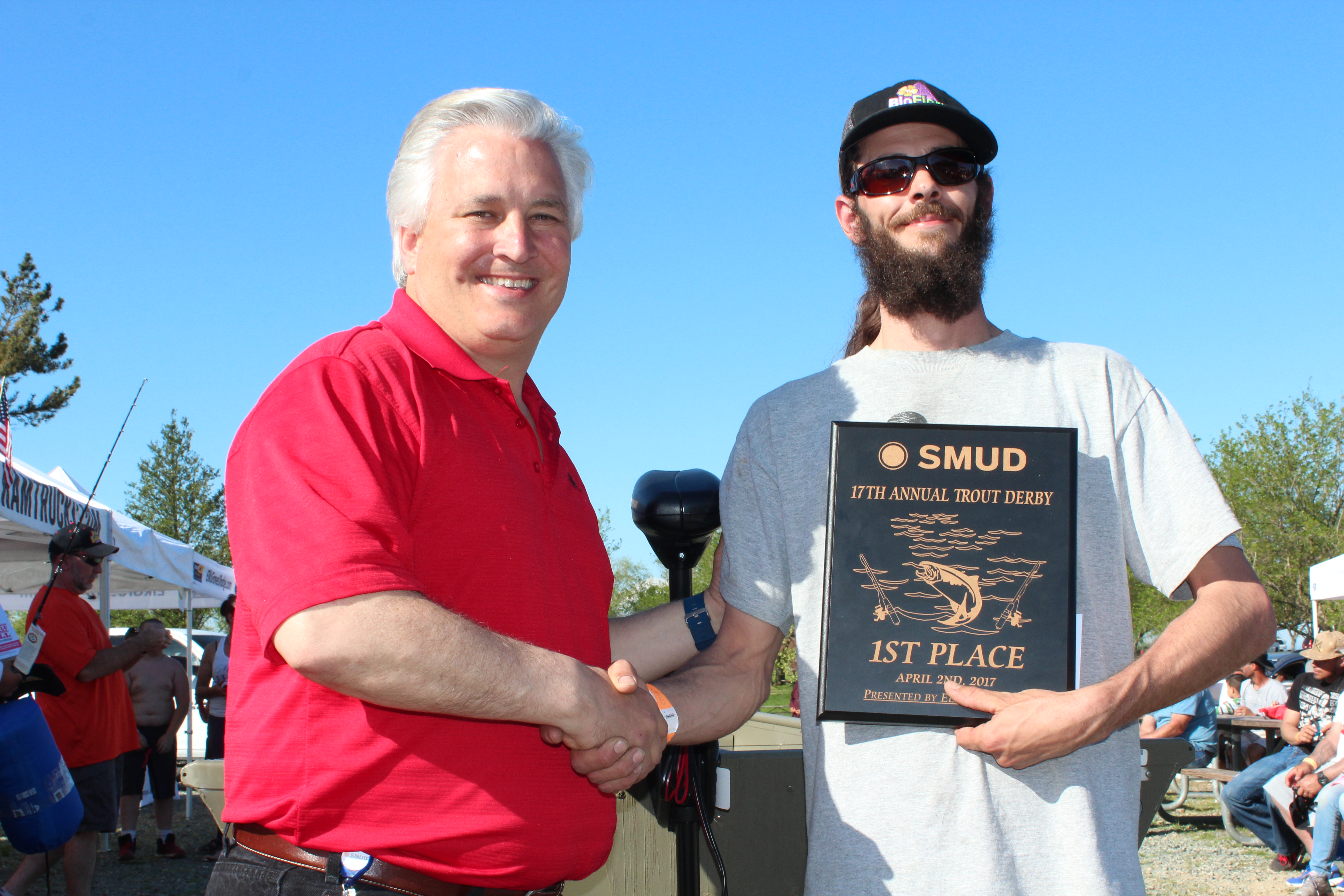 Al Ernst, SMUD’s Facilities and Maintenance Supervisor, congratulates Jarred Ross, the first place winner in the adult division on day two of the derby , in front of the14 foot Tracker with a Minn Kota trolling motor that Ross won. 